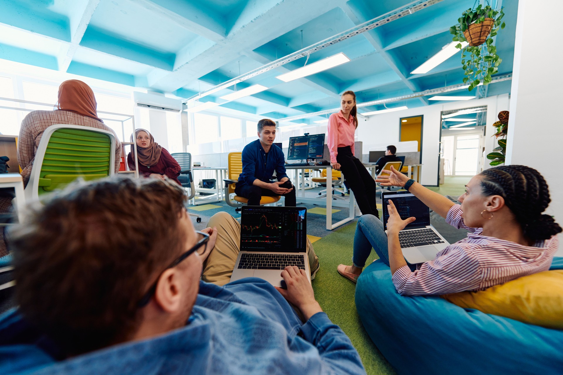 In a modern startup office, a diverse group of young and capable businesspeople engage in lively discussions about various projects, showcasing teamwork, innovation, and entrepreneurial spirit
